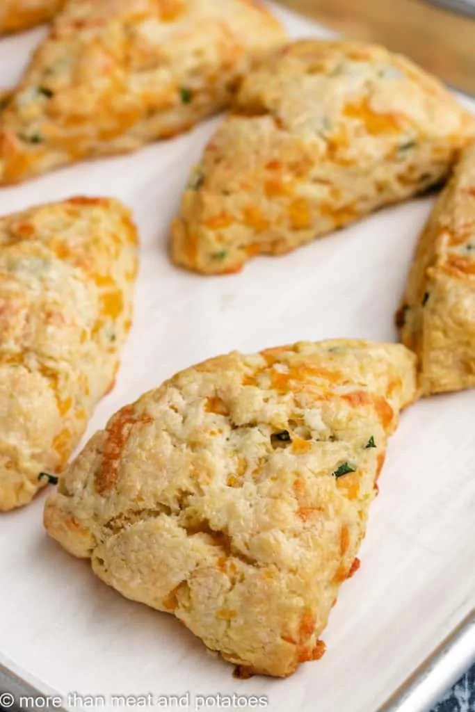 Five cheesy scones on the lined sheet pan.