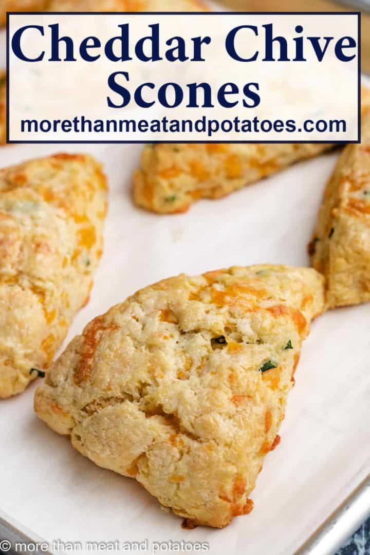 Cheddar chive scones on a sheet pan lined with parchment paper.