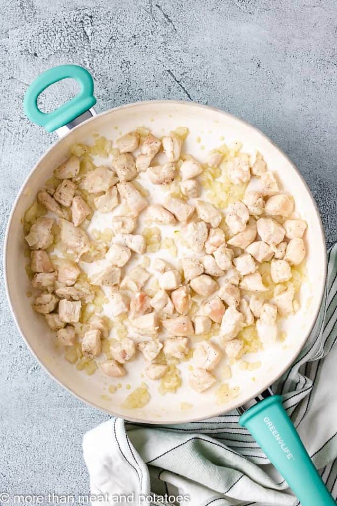 Onions and chicken breast cooking in the skillet.