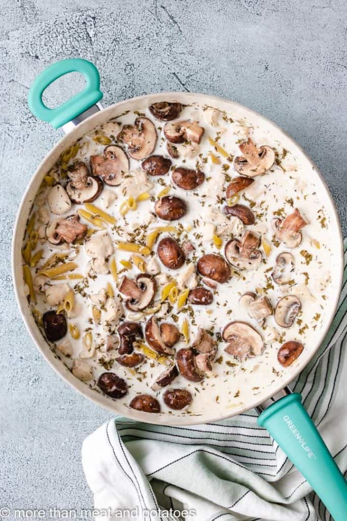 Heavy cream, broth, and dry pasta added to the skillet.