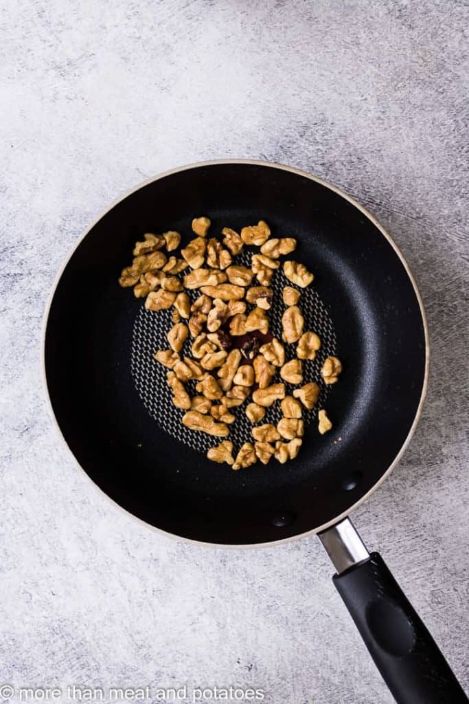 Walnuts toasting in a small saucepan.