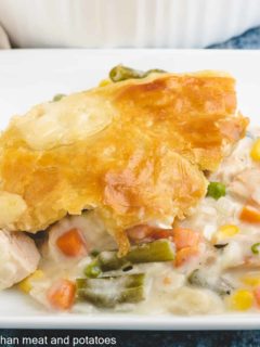 A serving of turkey pot pie with puff pastry on a plate.