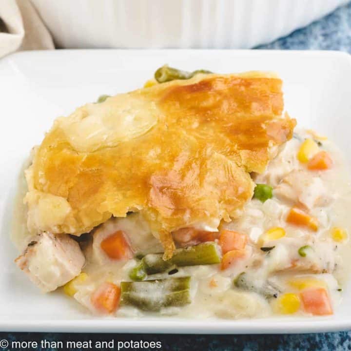 A serving of turkey pot pie with puff pastry on a plate.