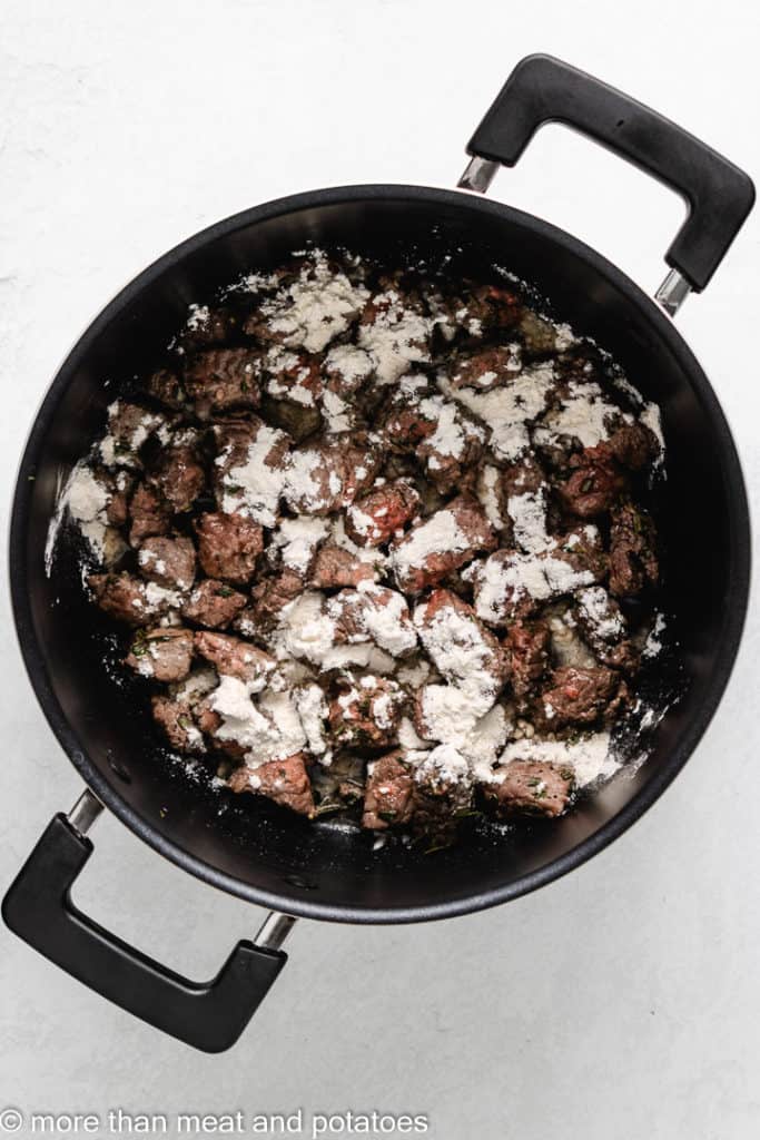 All-purpose flour sprinkled over the meat in the pot.