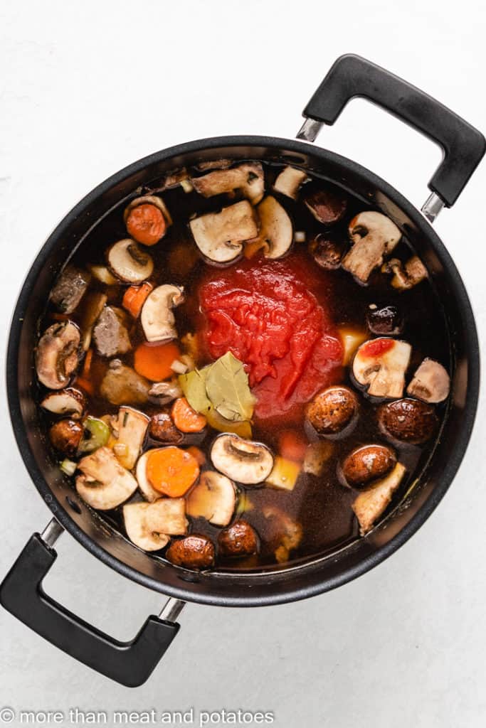 Broth, bay leaves, and tomato sauce added to the pot.