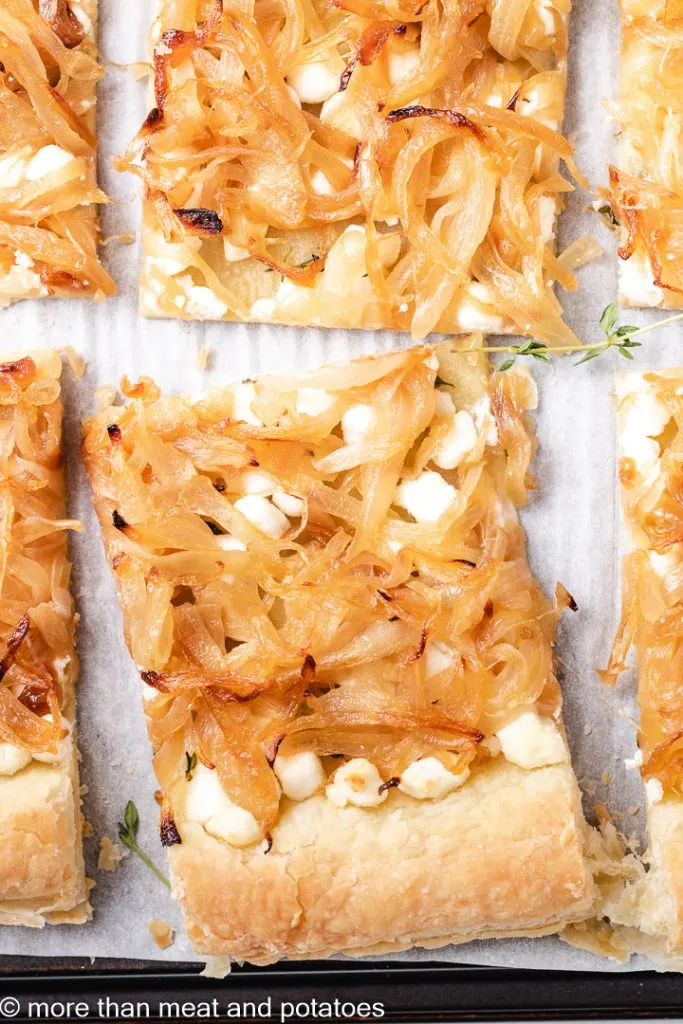 The savory baked tart sliced on a sheet pan.