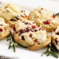 The cranberry brie crostini bites served on a white platter.