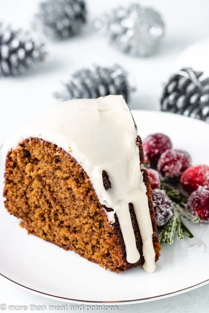 Slice of gingerbread cake next to silver pinecones.