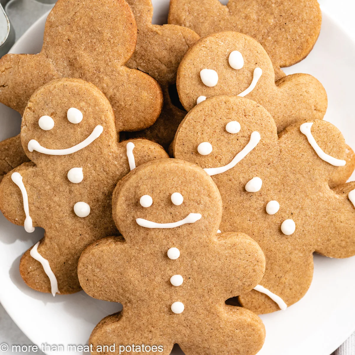 Decorated and undecorated gingerbread cookies stacked on a plate.