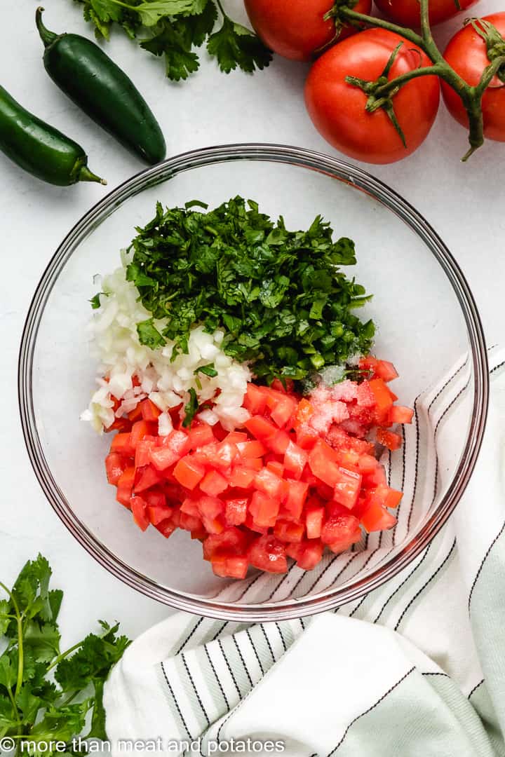 Tomatoes, jalapenos, onions, and lime juice in a bowl.