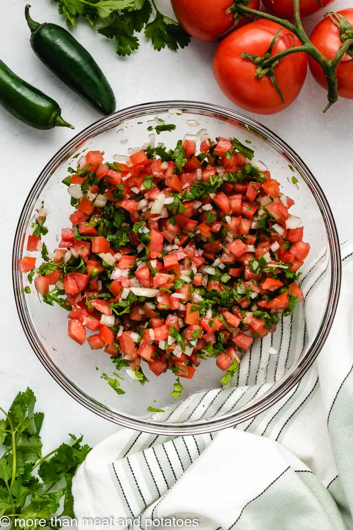 Tomatoes, jalapenos, onions, and lime juice stirred in a bowl.