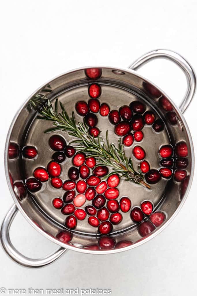 Cranberries and rosemary in a pot with simple syrup.