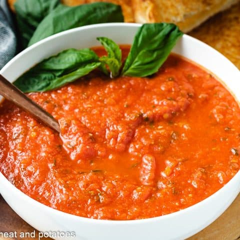 Tomato soup with basil in a white bowl.