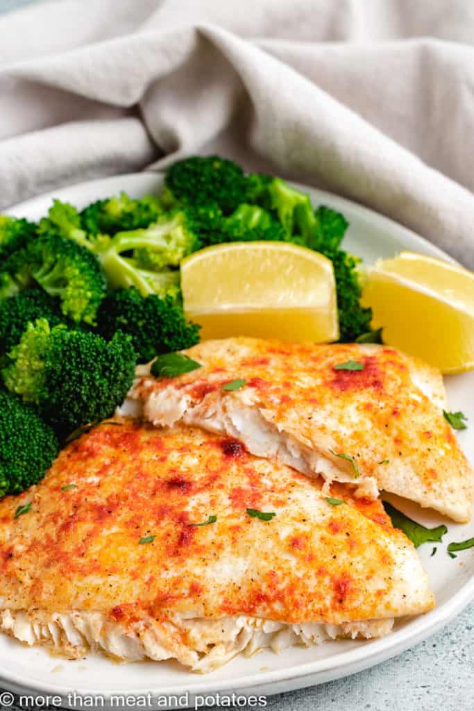 Baked fish with fresh veggies on a gray plate.