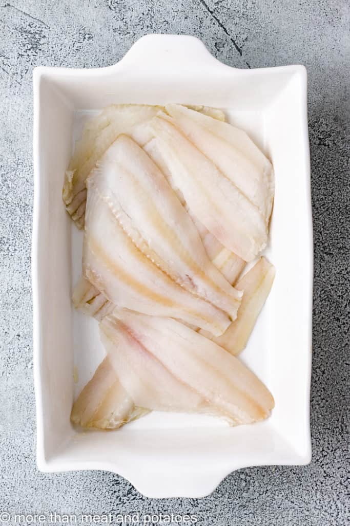 Flounder fillets in a white baking dish.