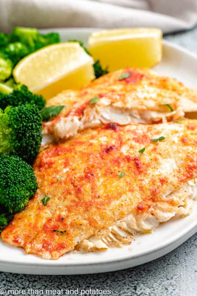 Baked flounder with lemon wedges.