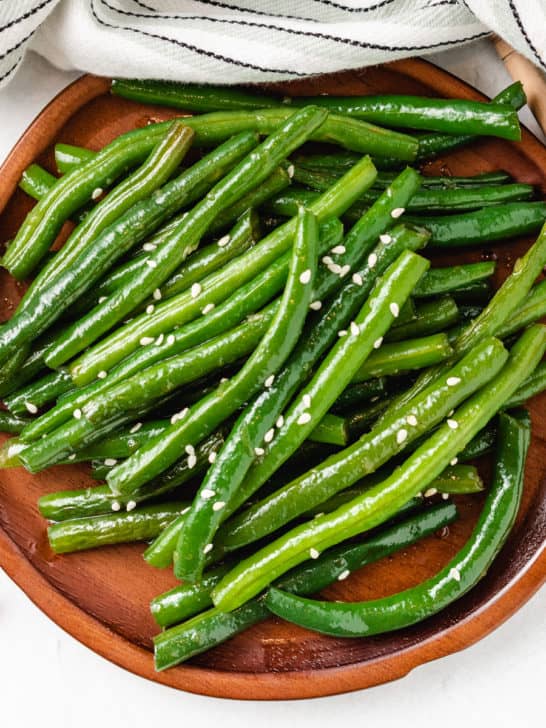 Top down view of Honey Garlic Green Beans on a wooden plate.