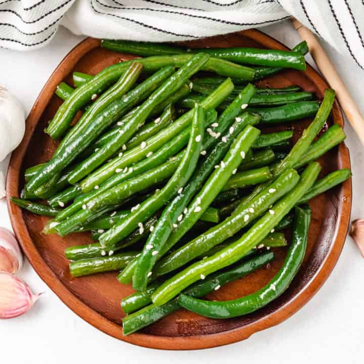 Honey Garlic Green Beans Top down view of Honey Garlic Green Beans on a wooden plate.
