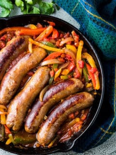 Top down image of Italian sausage and peppers in a cast iron skillet.
