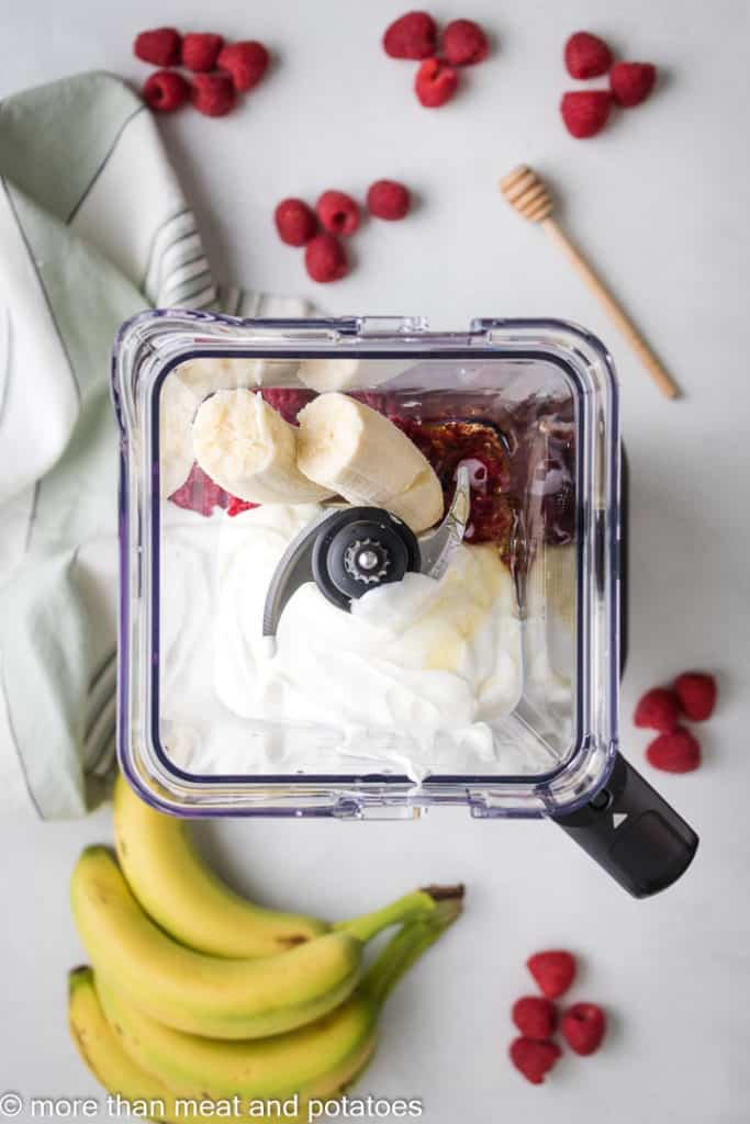 Banana, honey, raspberries, and yogurt in a blender.