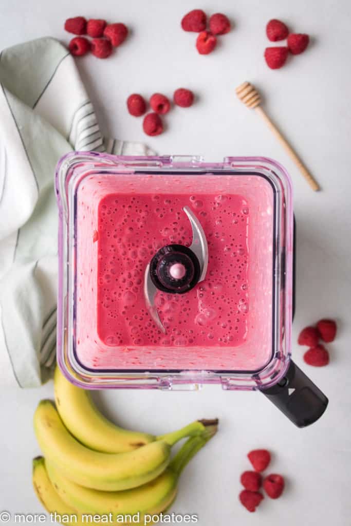 Top down view of a raspberry smoothie in a blender.
