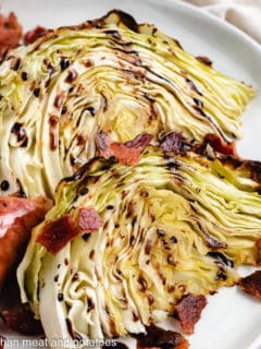 Two cabbage wedges with crumbled bacon and sausage.