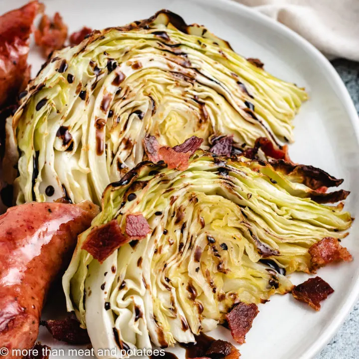 Two cabbage wedges with crumbled bacon and sausage.