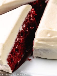 Slice of red velvet cake being pulled from the whole cake.