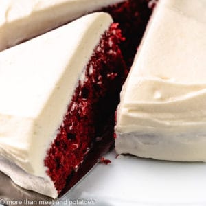 Slice of red velvet cake being pulled from the whole cake.