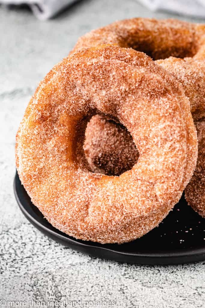 Large cinnamon sugar donut on a black plate.