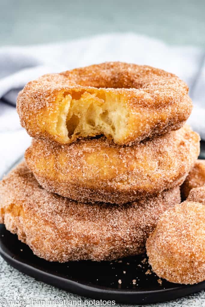 Cinnamon sugar doughnuts with a bite taken out.