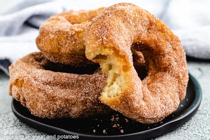 Sourdough doughnuts stacked against each other on a plate.  