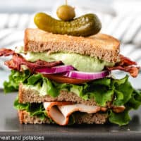 Turkey avocado club on a black plate.