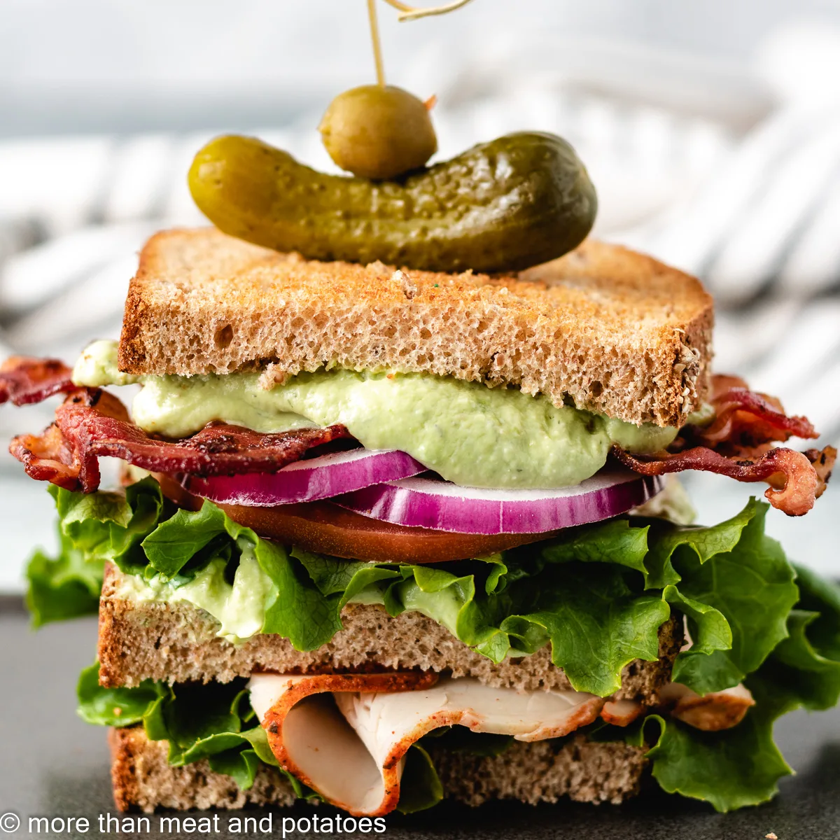 Turkey club with avocado ranch and a pickle.