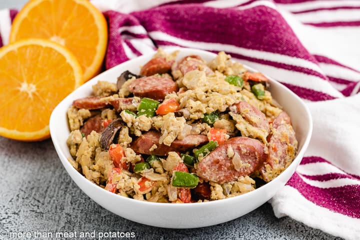 White serving bowl filled with sausage, veggies, and scrambled eggs.