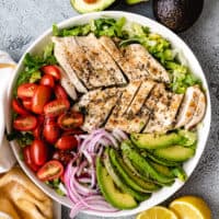 Top down view of chicken, tomatoes, and avocado on a salad.