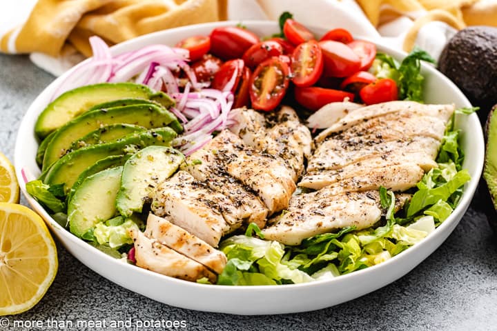 Chicken, avocado, and tomatoes on a salad.