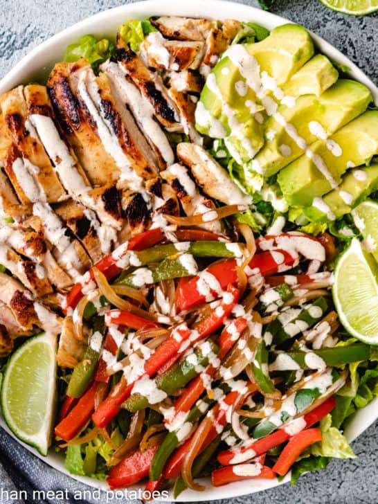 Top down view of chicken fajita salad with avocado slices.