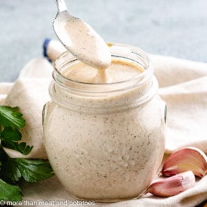 Spoon being stirred in a jar of dressing.