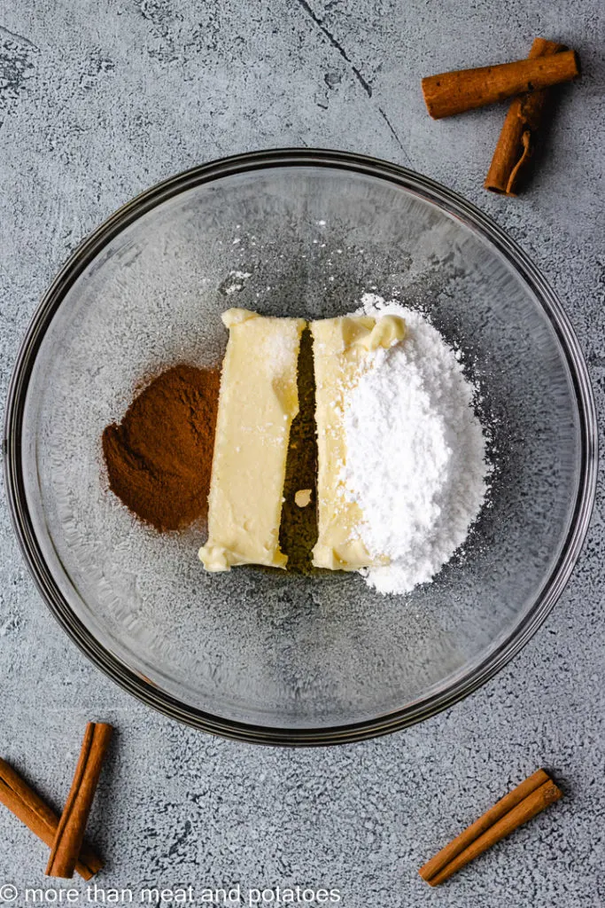 Top down view of butter, powdered sugar, vanilla, and cinnamon in a bowl.