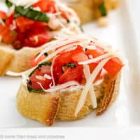 Bruschetta topped with parmesan cheese and cream cheese.