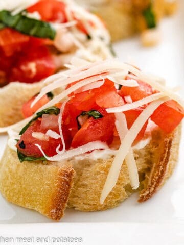 Bruschetta topped with Parmesan cheese and cream cheese.