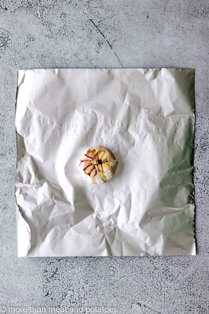 Bulb of garlic on a piece of aluminum foil.