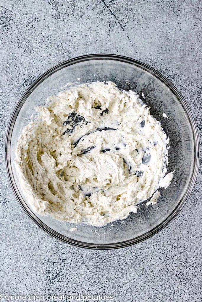 Top down view of cream cheese with herbs in a glass bowl.
