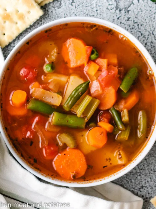 Top down view of vegetable soup in a bowl with crackers.