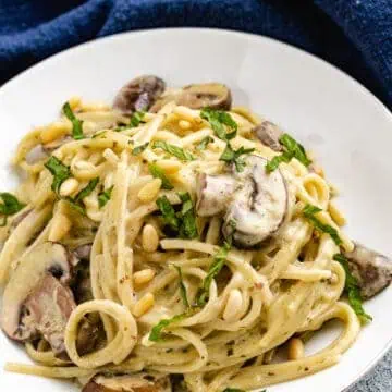 Pasta on a plate with mushrooms and pesto.