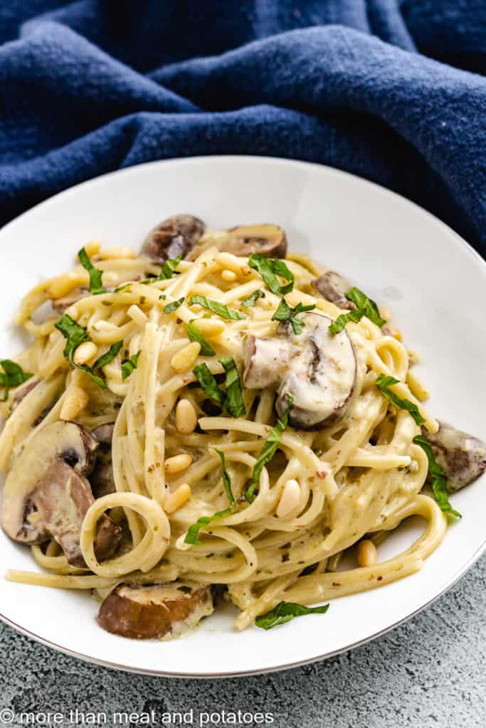 Pasta on a plate with mushrooms and pesto.