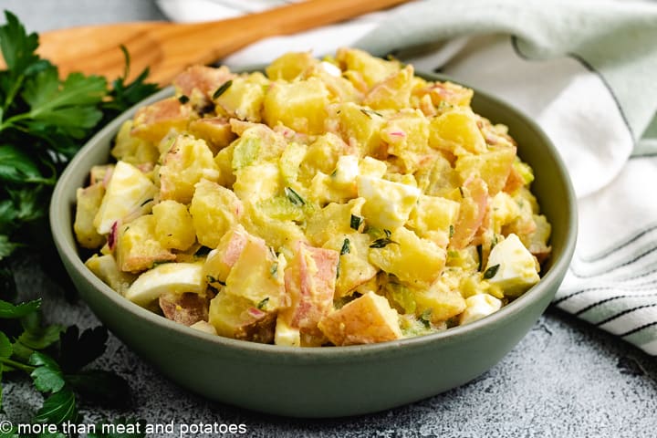 Potato salad in a serving bowl with a spoon.