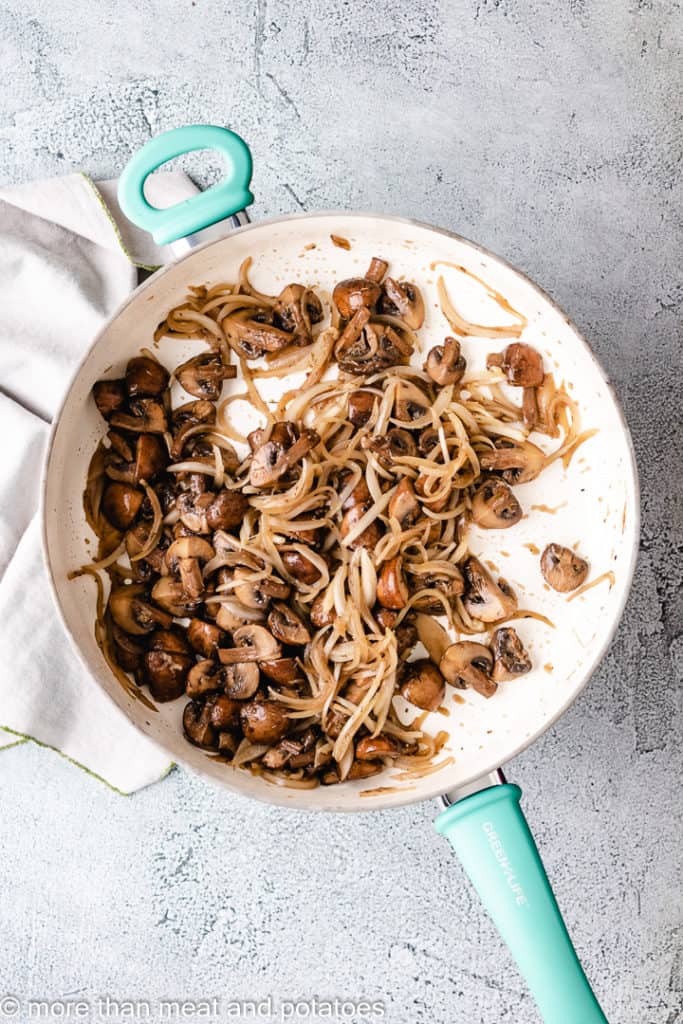 Seasoned mushrooms and onions in a skillet.