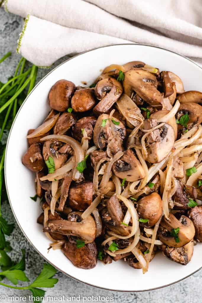 Top down view of seasoned mushrooms and onions on a plate.